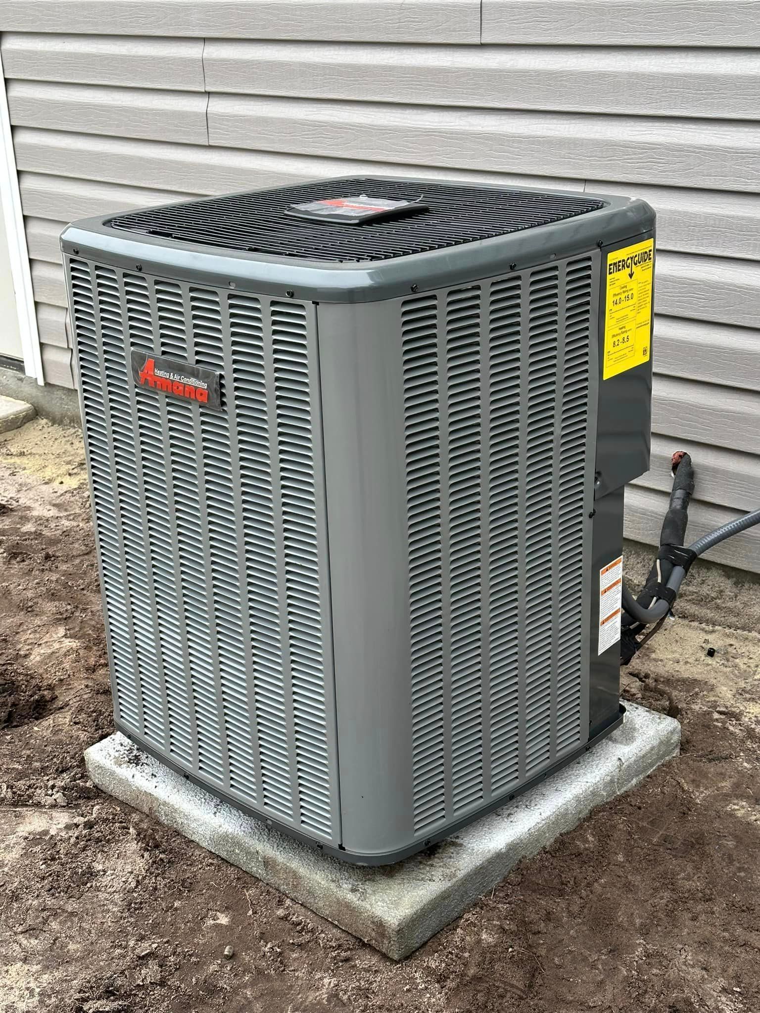 A large air conditioner is sitting on top of a concrete base in front of a house