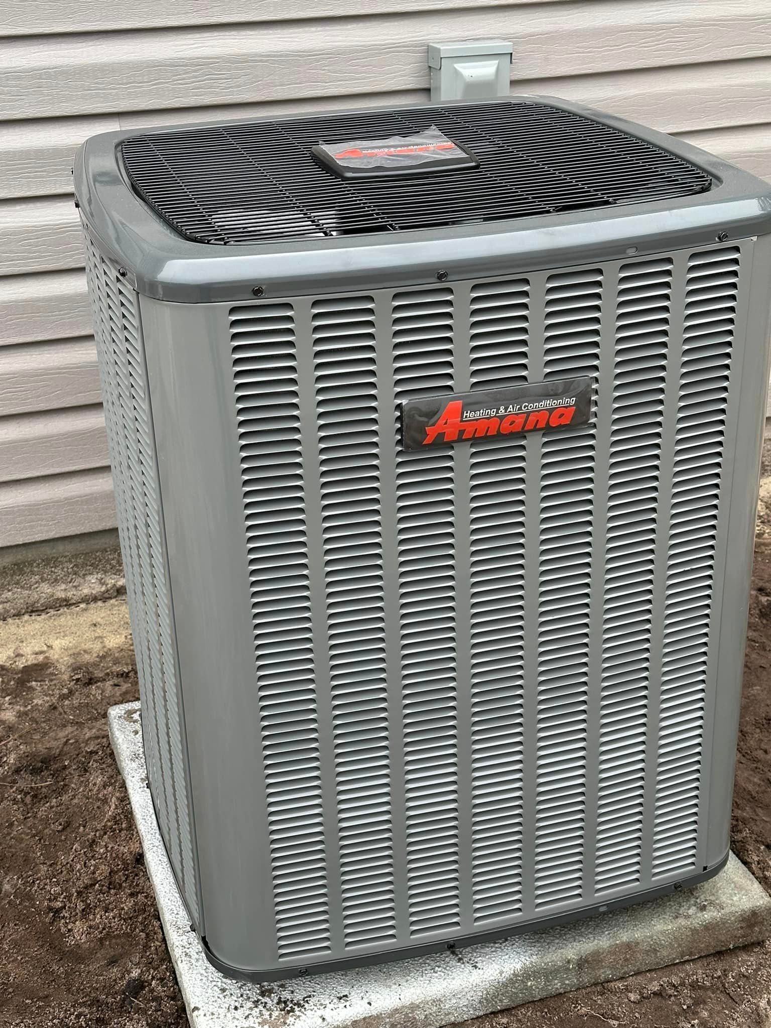 A large air conditioner is sitting on top of a concrete base next to a house