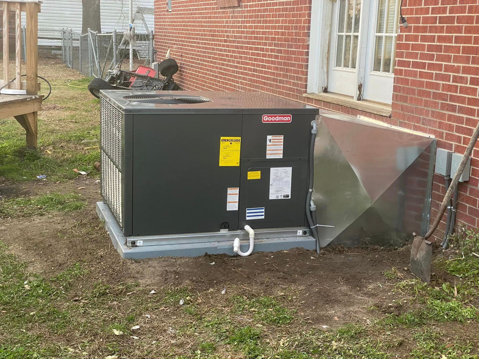 A black box is sitting in the grass in front of a brick building