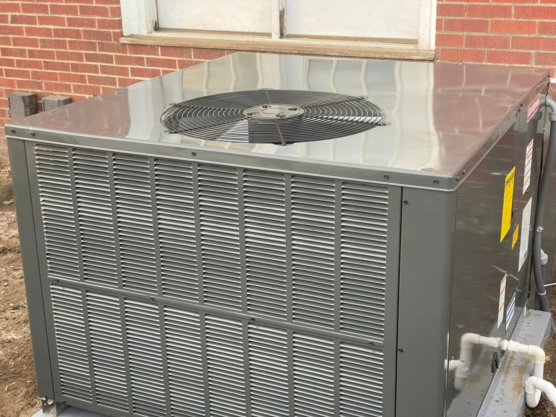 A large air conditioner is sitting outside of a brick building