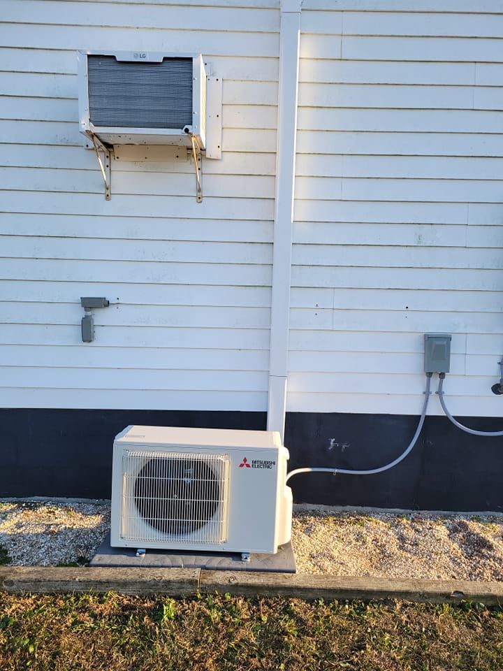 A white air conditioner is mounted on the side of a white house