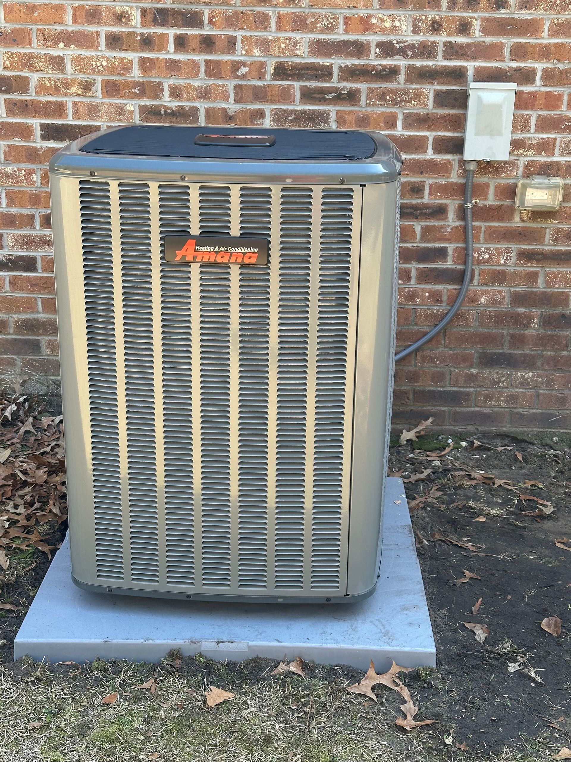 An air conditioner is sitting outside of a brick building.