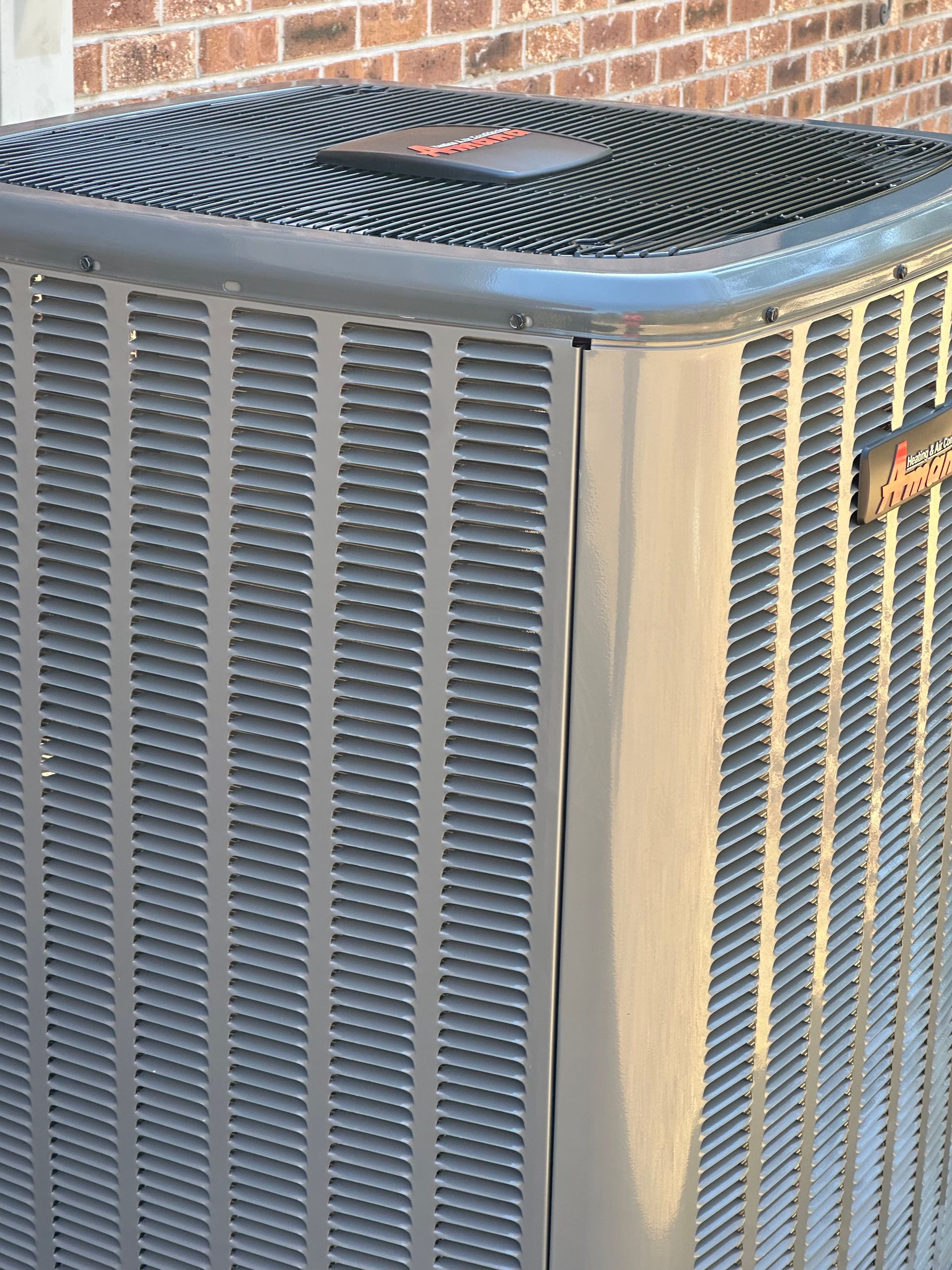 An air conditioner is sitting outside of a brick building.