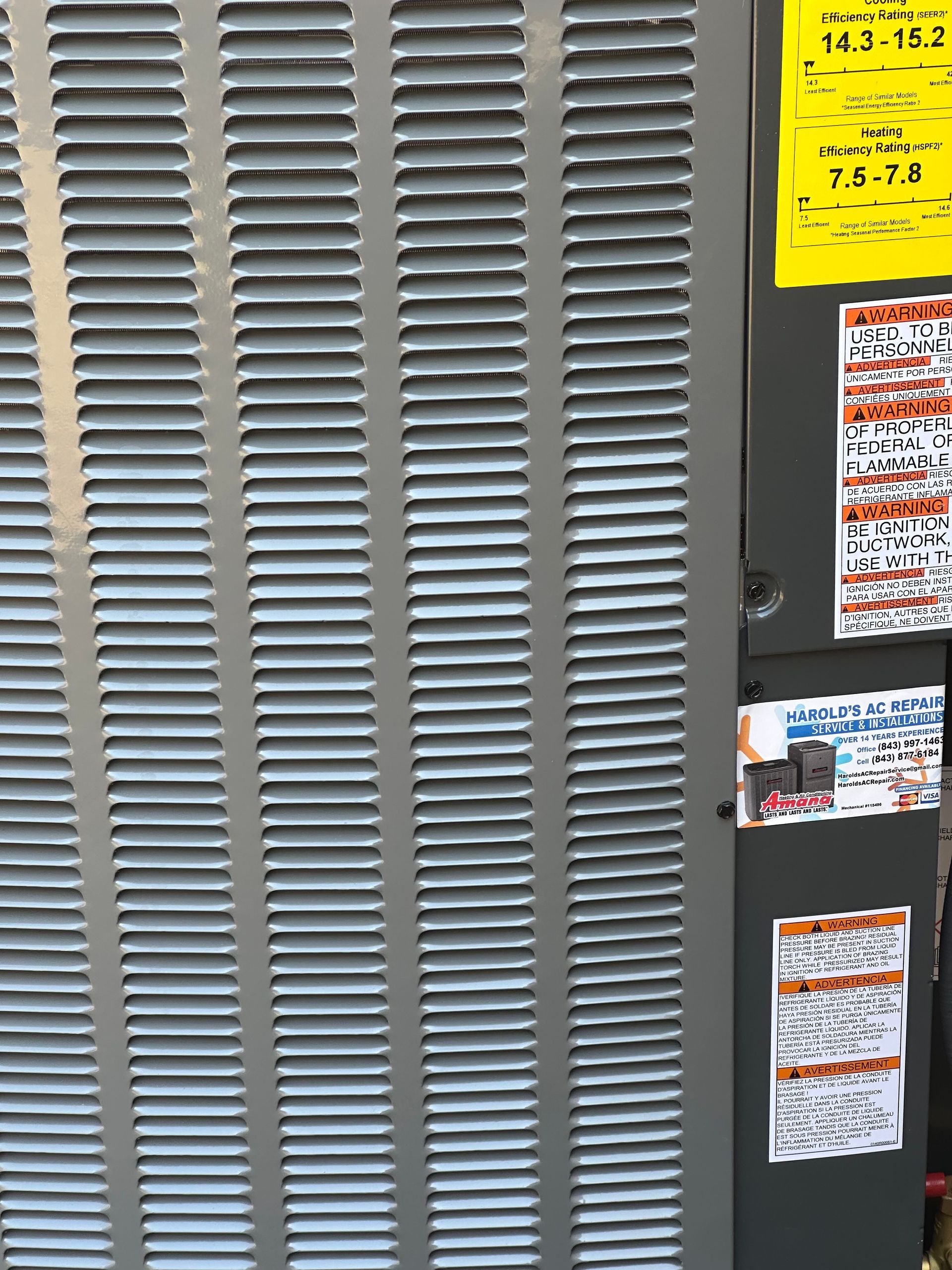 A close up of an air conditioner with a yellow sticker on it