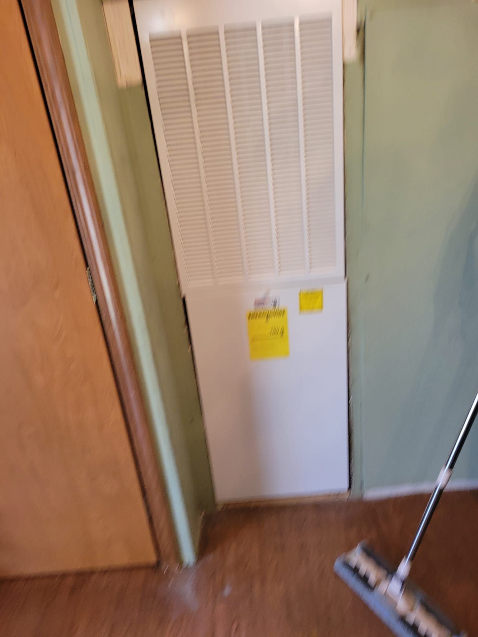 A mop is sitting on the floor next to a wall mounted air conditioner