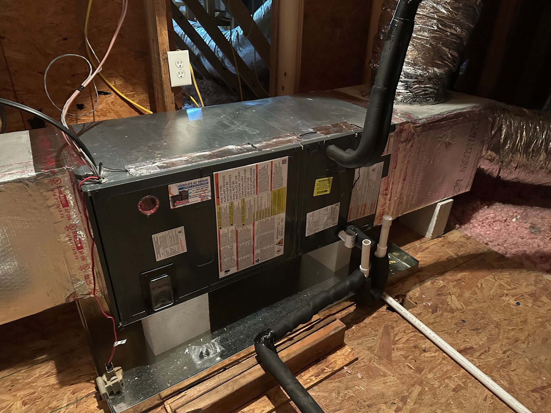 An air conditioner is sitting in the attic of a house.