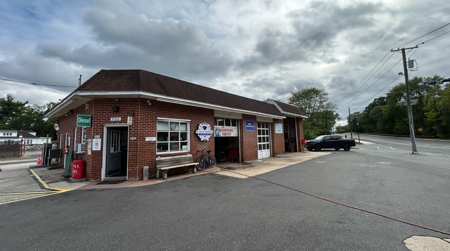Small brick storefront with red awning beside an empty parking lot under cloudy skies