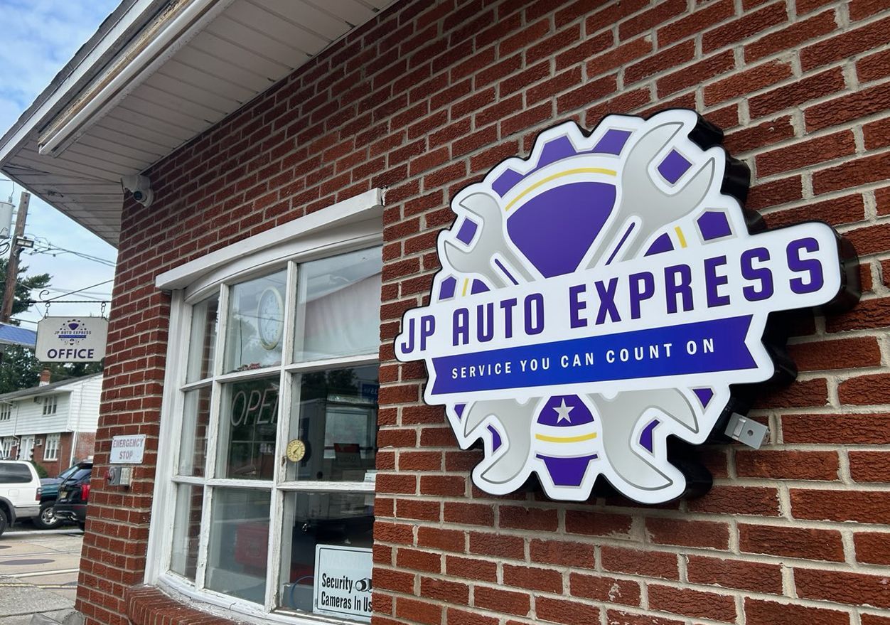 JP Auto Express sign on a red brick building, with white-framed windows and a gray awning.