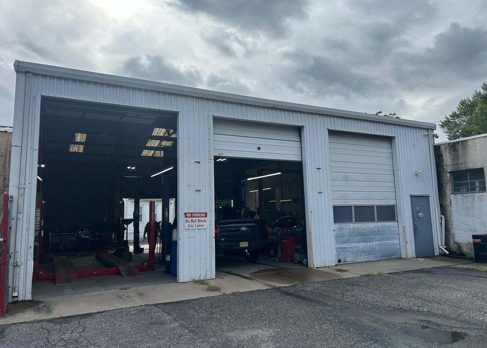 Auto repair shop exterior with open garage bays under a cloudy sky