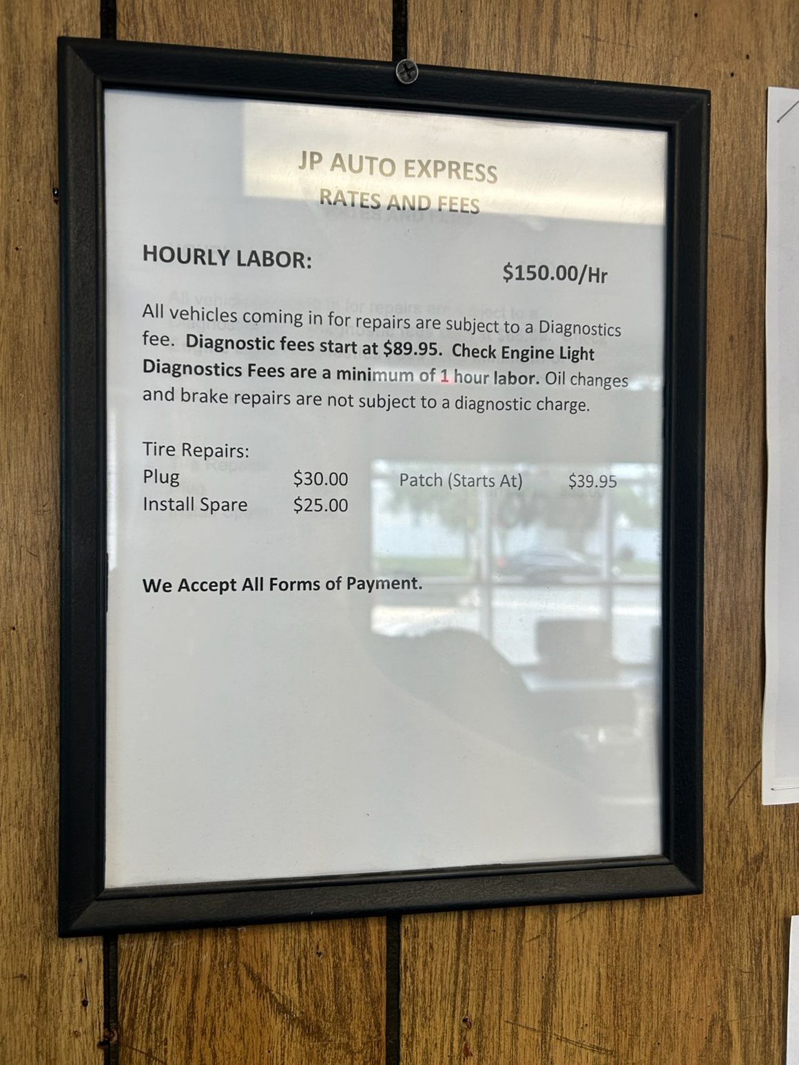 Framed auto repair hourly labor rate sign on a wood wall