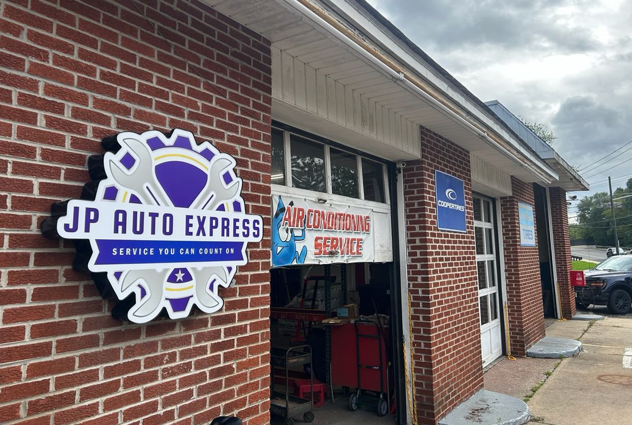 JP Auto Express storefront on a brick building with red and blue signage and an open entrance