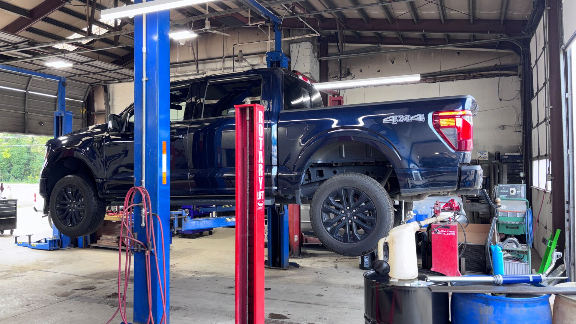 Black SUV on a car lift inside an auto repair shop with tools and equipment nearby