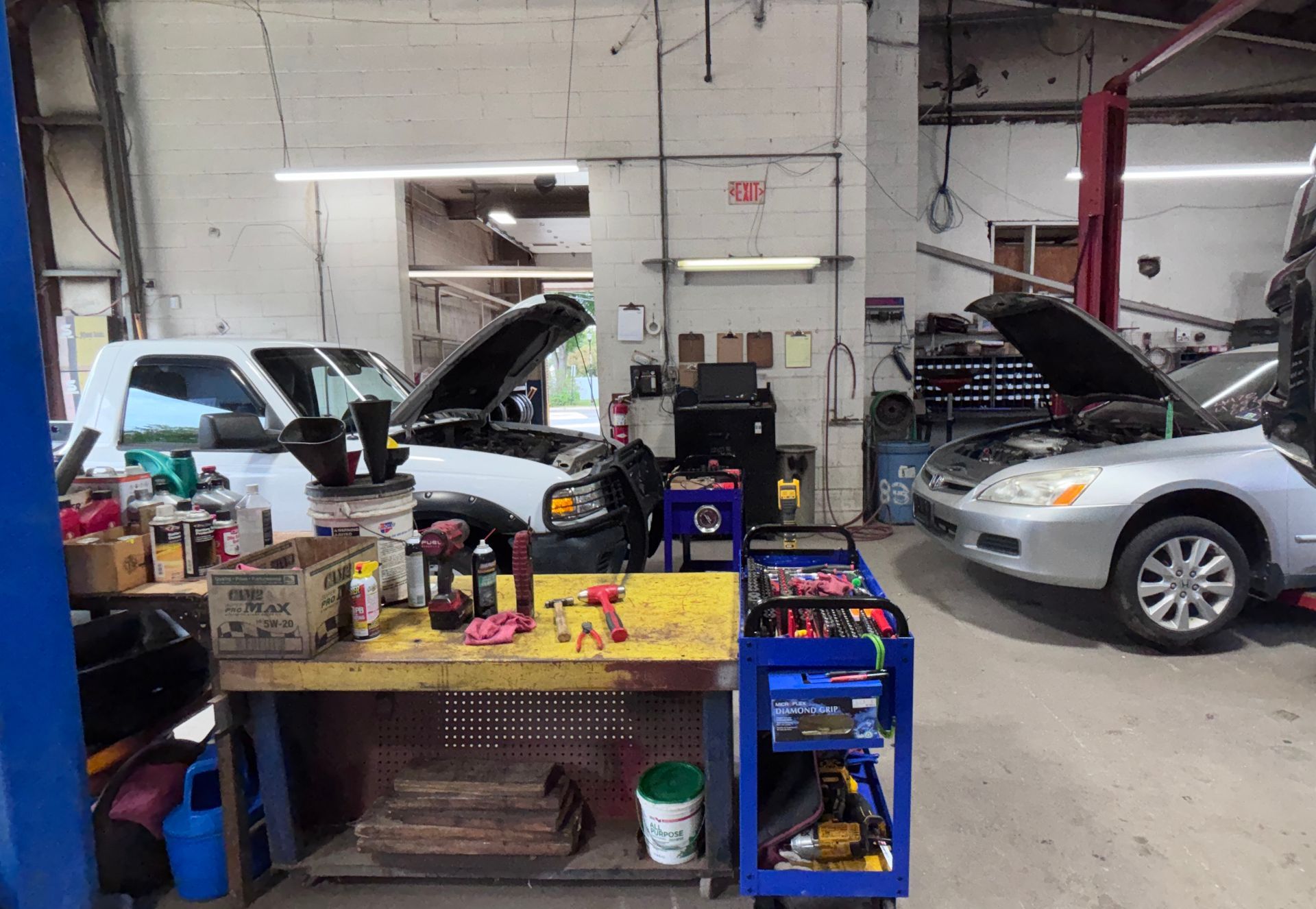 Auto repair shop with two cars lifted for repair and a workbench full of tools in the foreground