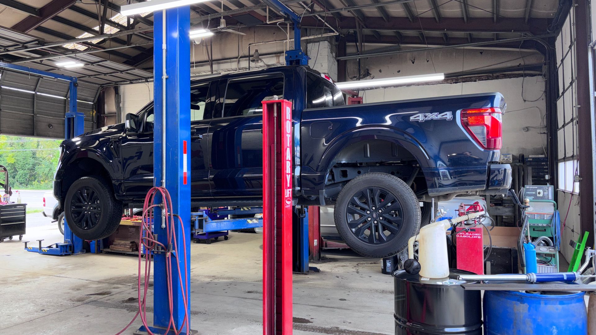 Black pickup truck on a lift in an auto repair shop with tools and equipment nearby