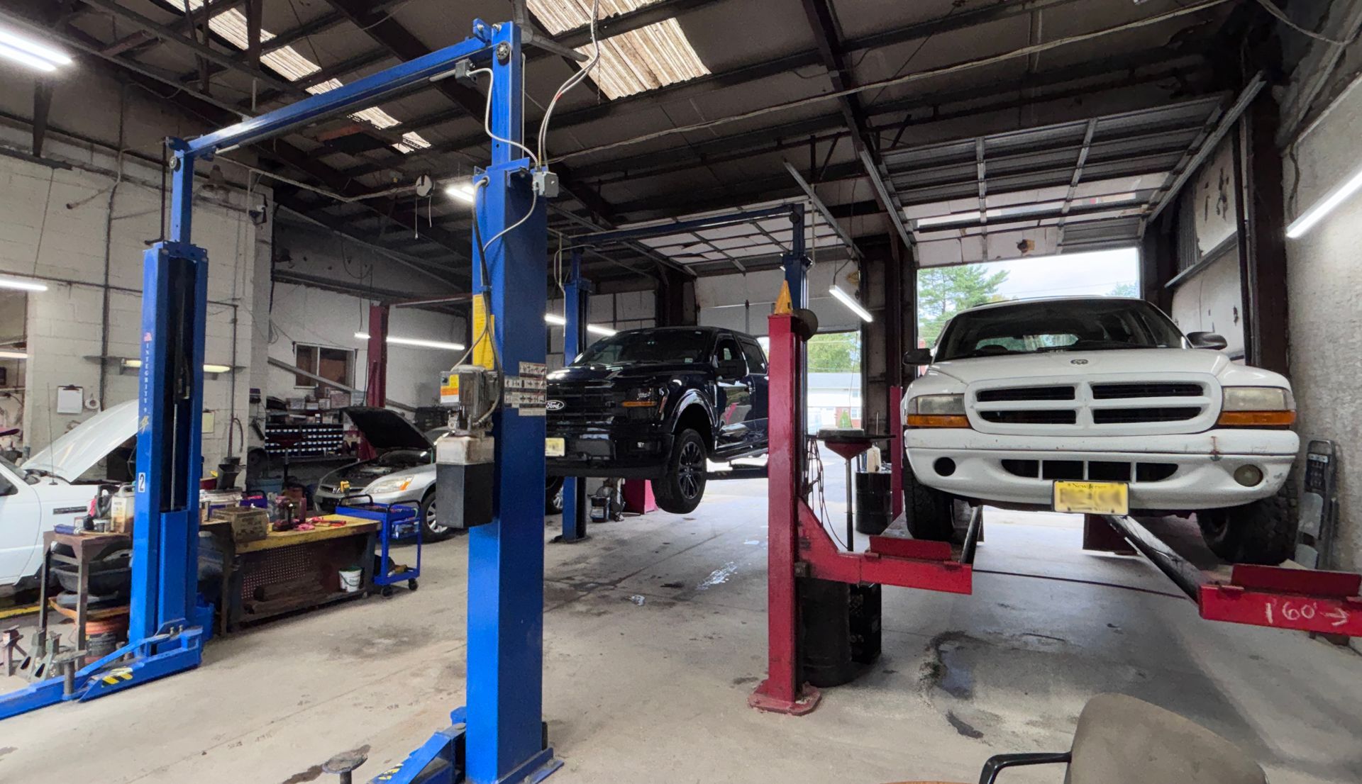 Auto repair shop with several cars on hydraulic lifts and a truck being serviced inside a garage.