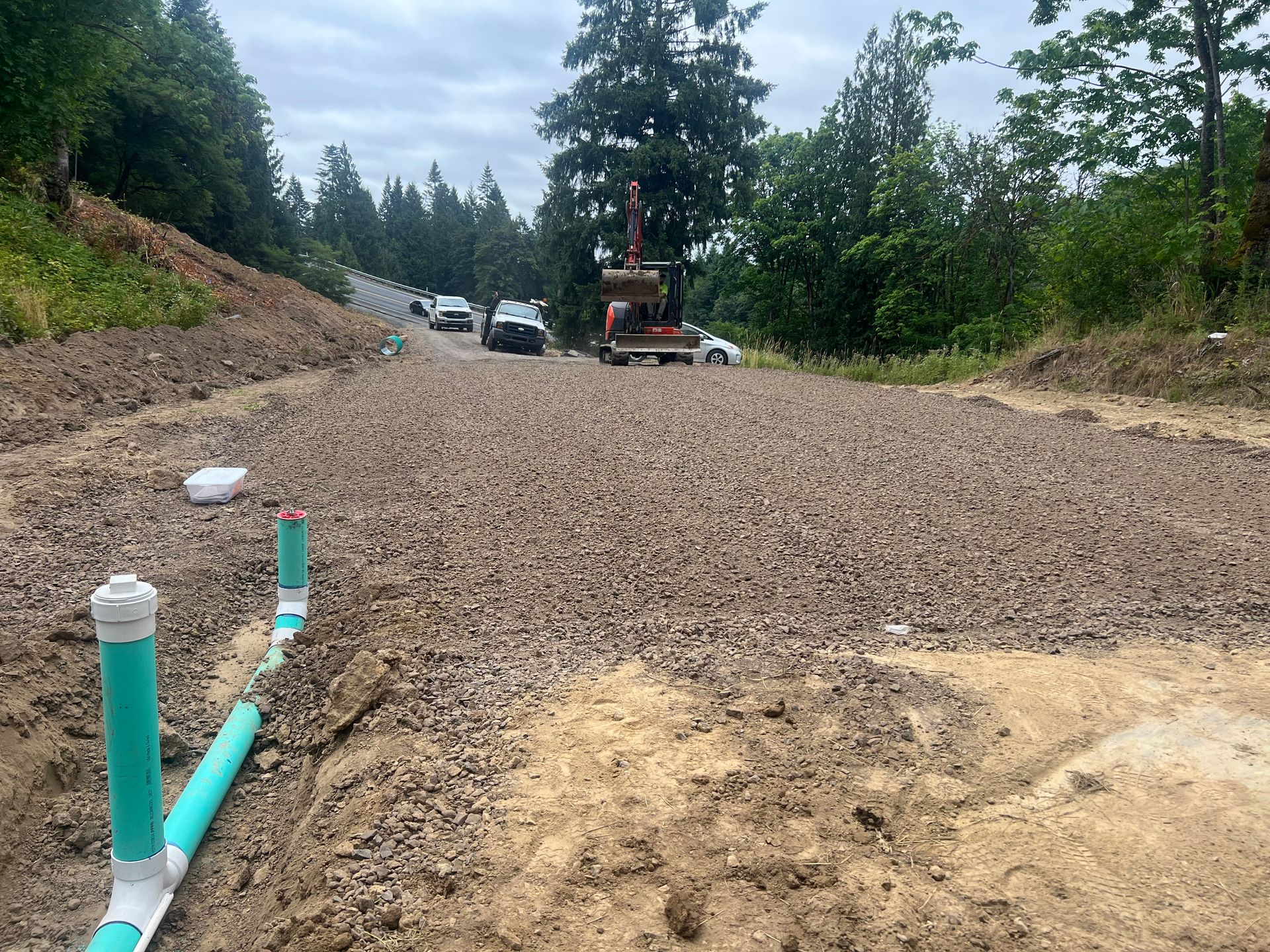 a truck is driving down a dirt road next to a row of green pipes