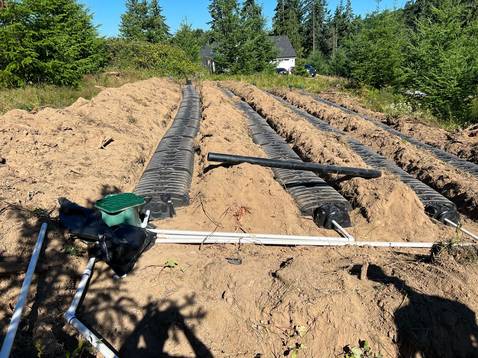 a row of dirt tracks in a field with a house in the background
