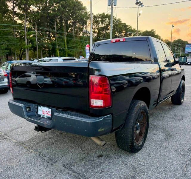 Black Ram pickup truck parked in a lot, showing the rear with taillights and exhaust, overcast sky.