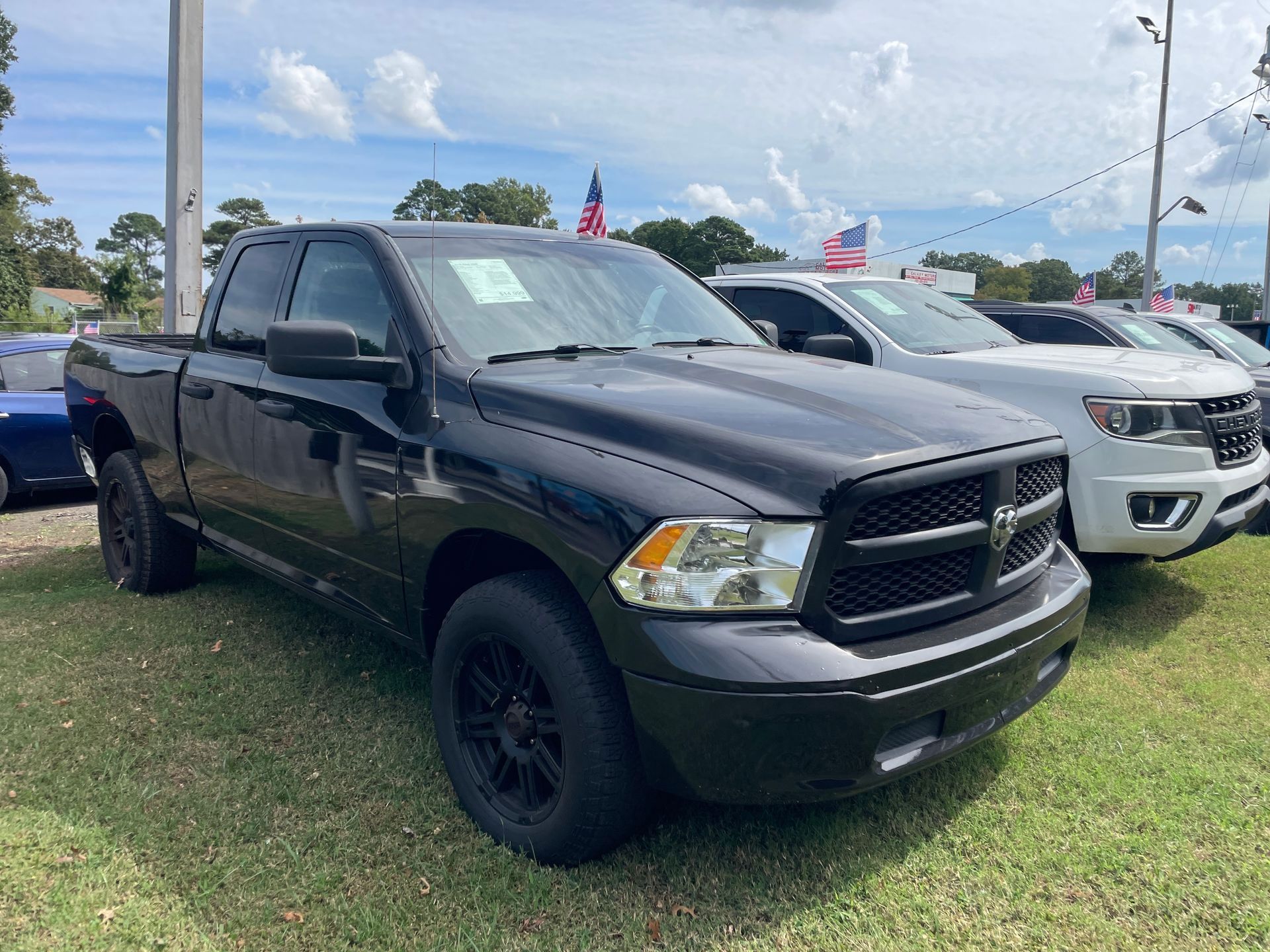 Black Ram pickup truck parked on a grassy lot at a car dealership.