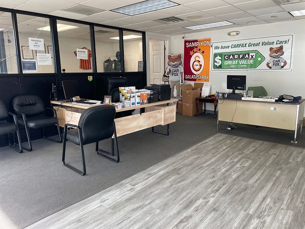 Office interior: desks, chairs, banners, and a computer.