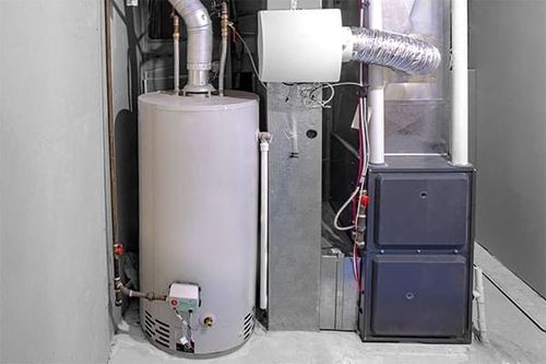 Utility room with water heater, furnace, and ductwork against a wall