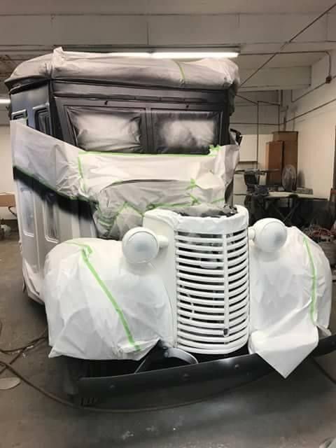 A white car is being painted in a garage.
