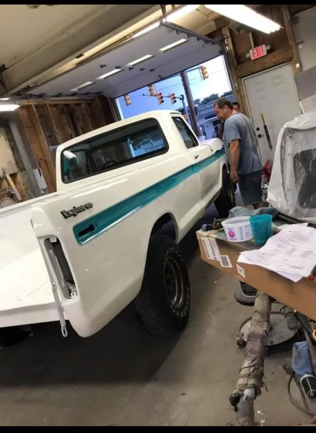 A white truck with blue stripes is parked in a garage.