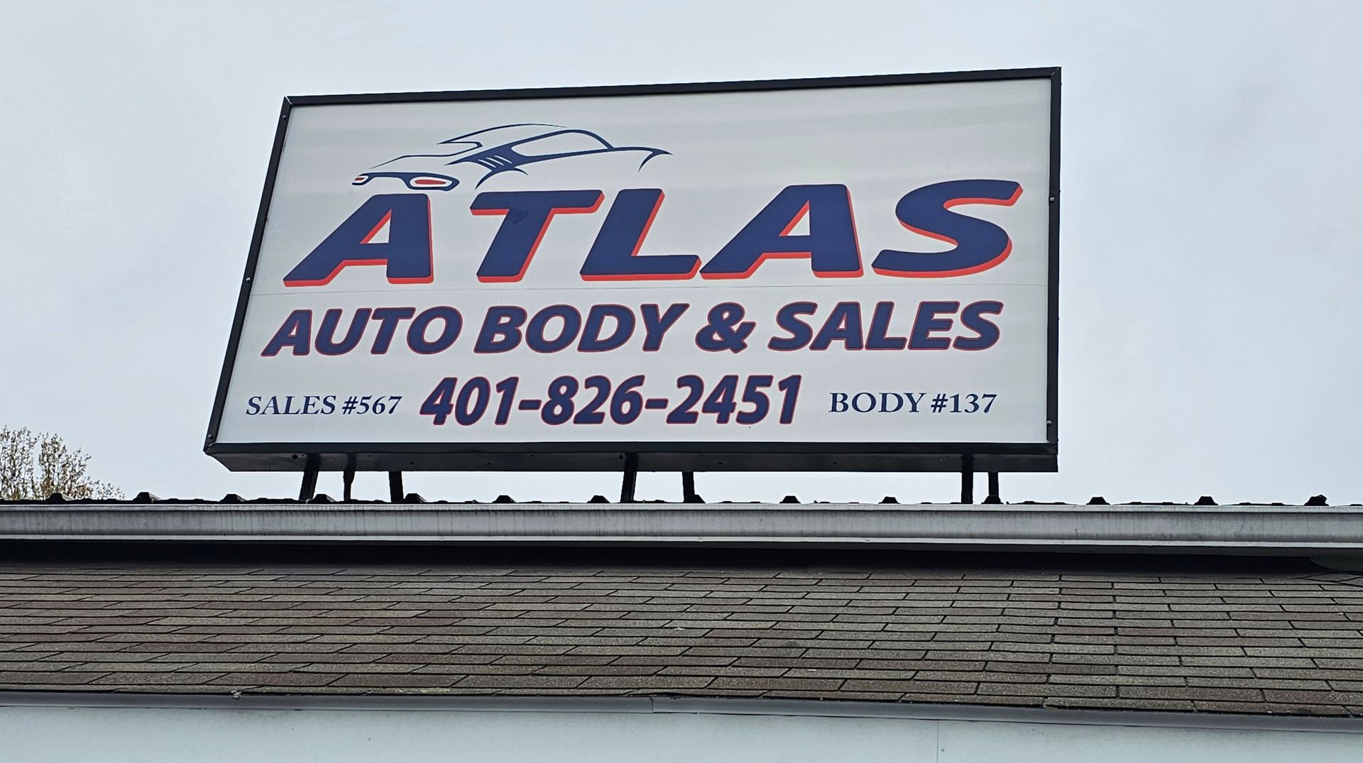 A billboard for atlas auto body and sales on top of a building