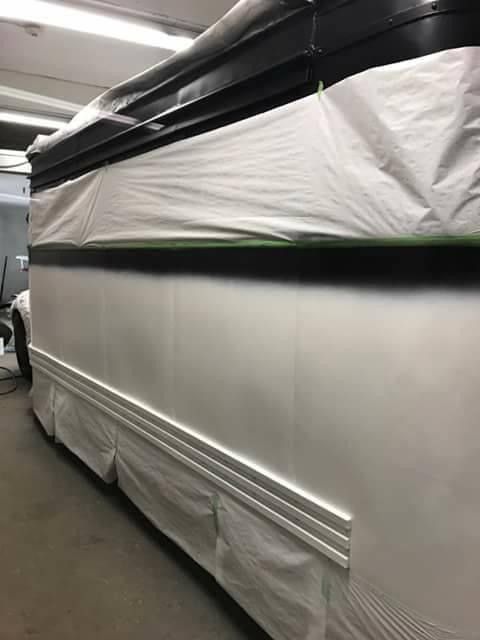 A white bus is wrapped in plastic and sitting in a garage.