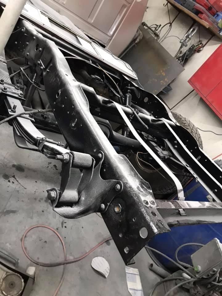 A car frame is sitting on the ground in a garage.