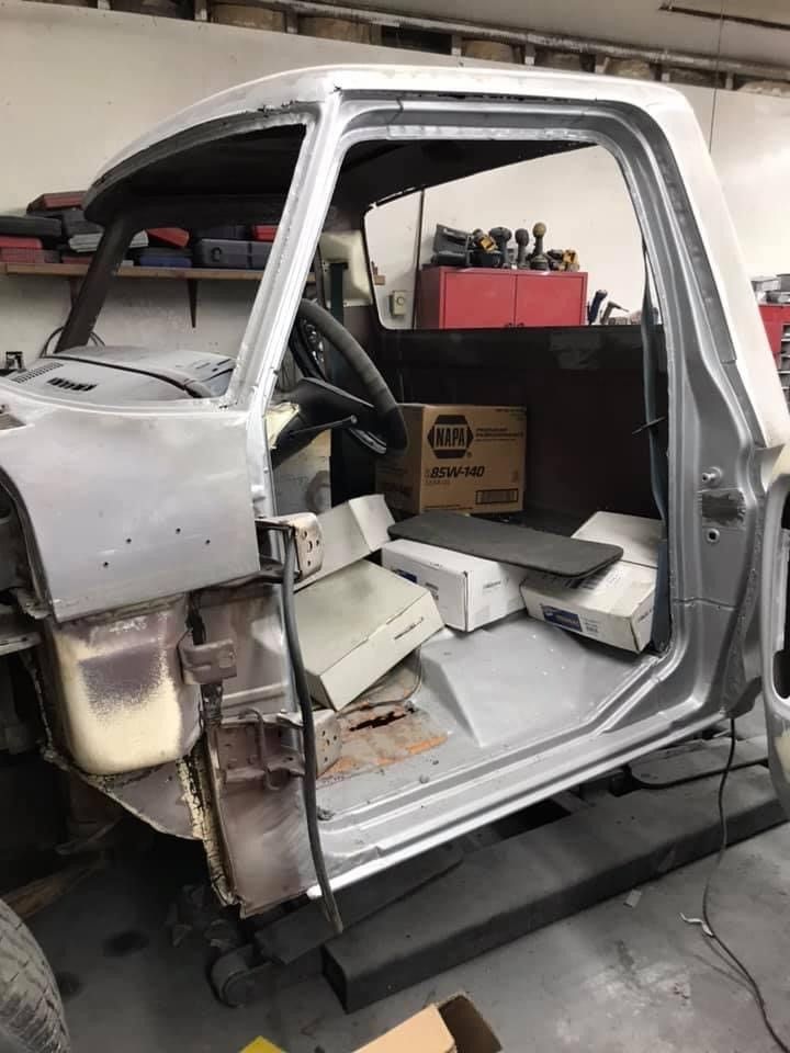 A truck is being built in a garage with the door open.