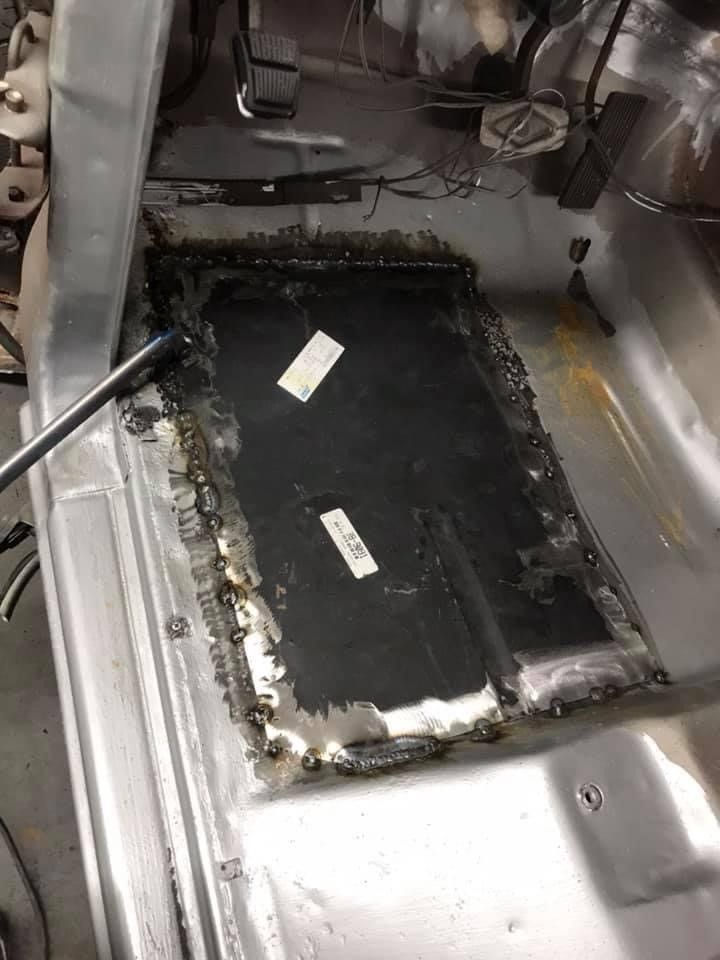 A car is being worked on in a garage with a wrench in it.