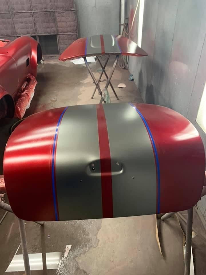 A red and gray car is being painted in a garage.