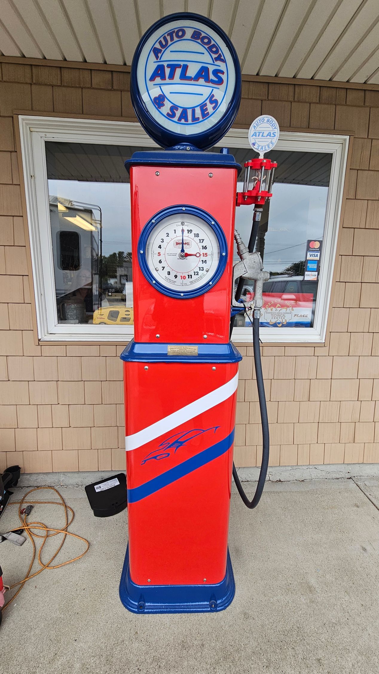 A red and blue gas pump with a clock on top of it.