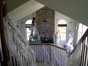 Stairway decorated with white draped fabric and a brick fireplace in a large room, viewed from an upper landing