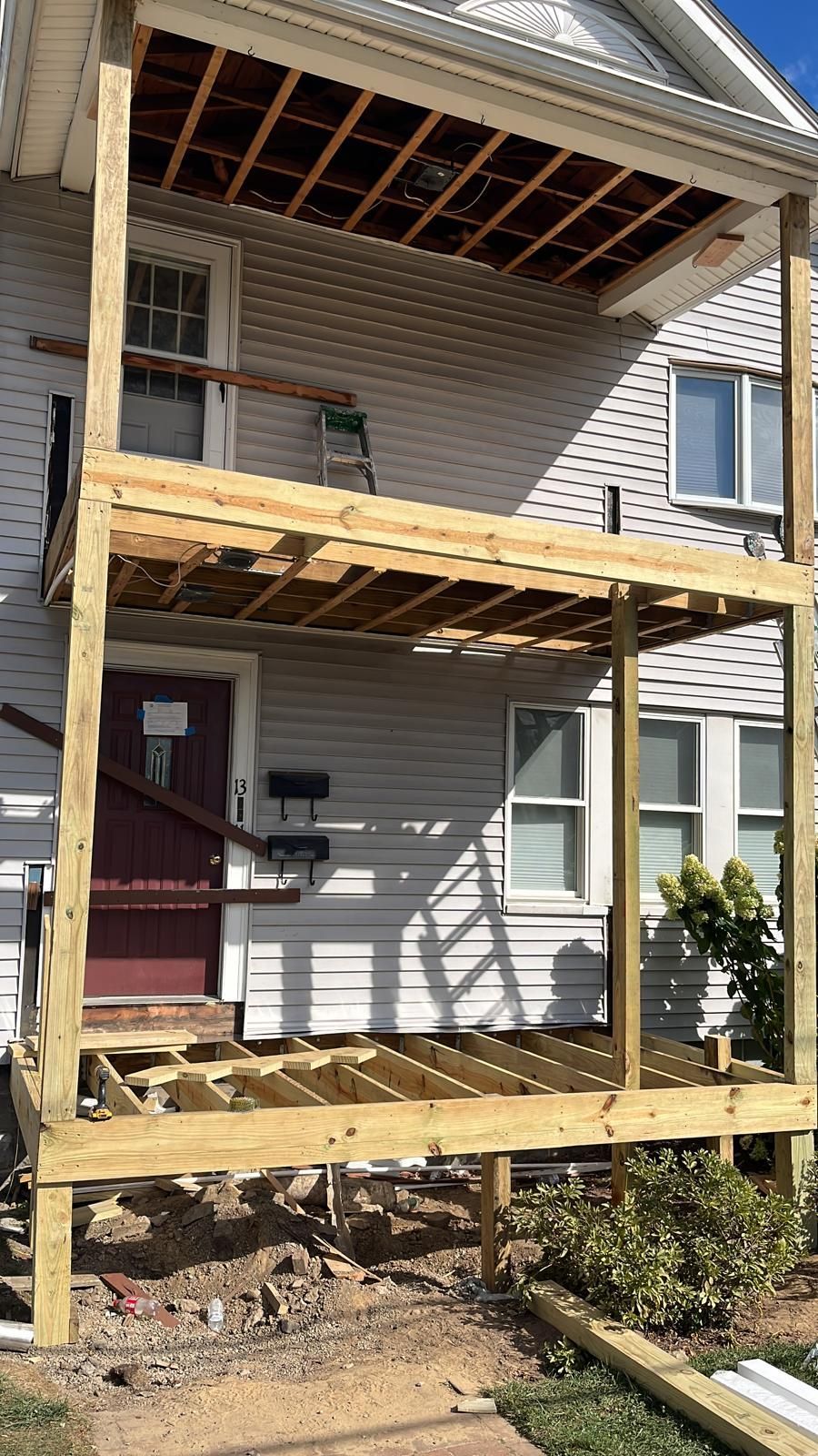 House exterior with a large unfinished wooden porch deck and supports under construction.