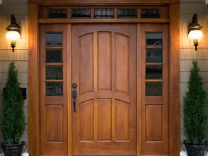Wooden front door with sidelights and lantern sconces at a home entrance