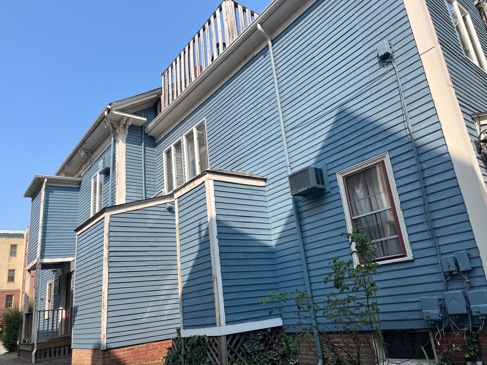 Blue wooden house exterior with white trim and balconies under a clear sky