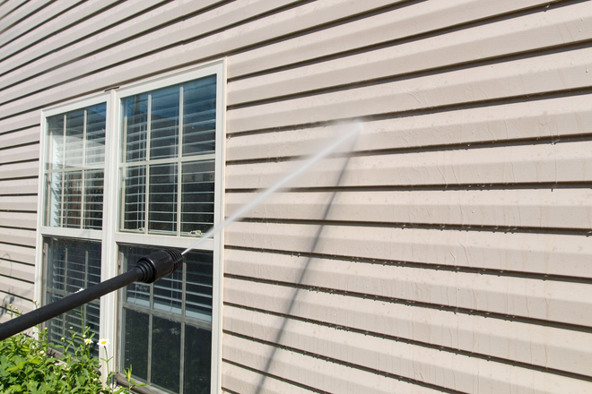 Exterior wall with white siding, window, and railing shadows in sunlight