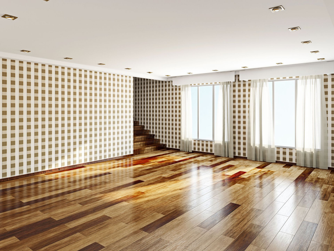 Empty bright room with hardwood floors, patterned walls, and large windows with curtains