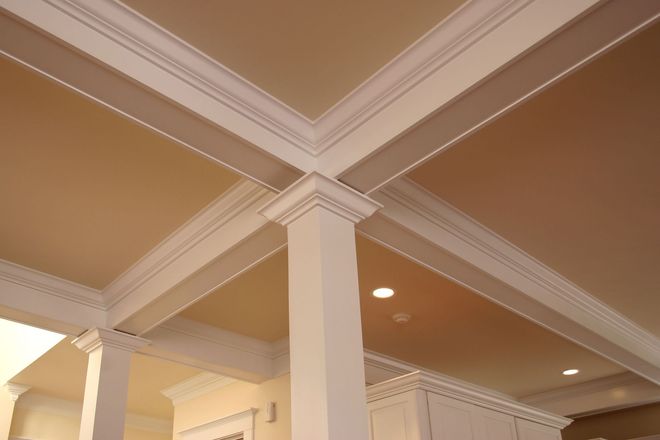 Interior ceiling with white crown molding and beige panels above columns.
