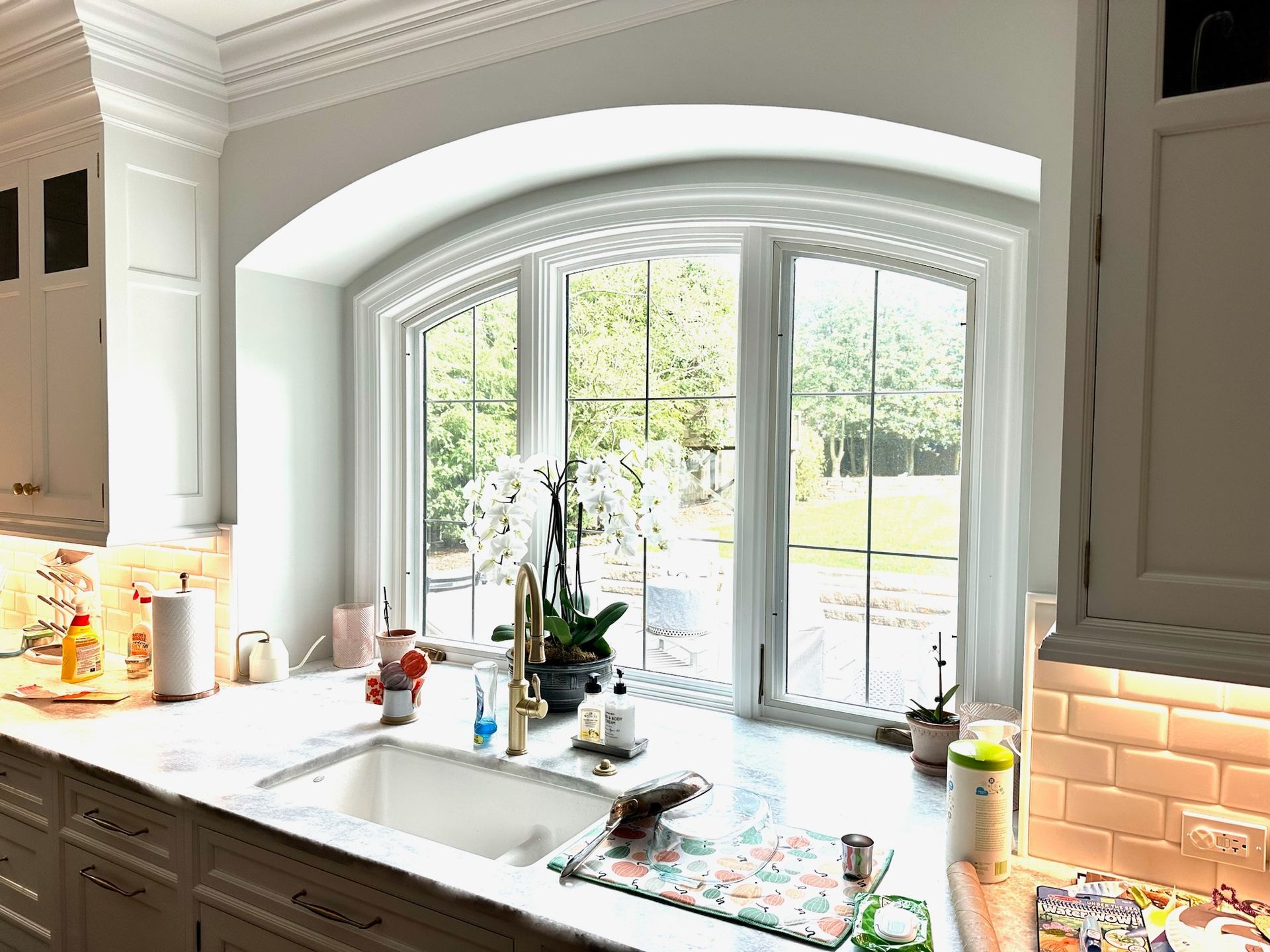 Kitchen with a white countertop, a large window, and an arch over the window.
