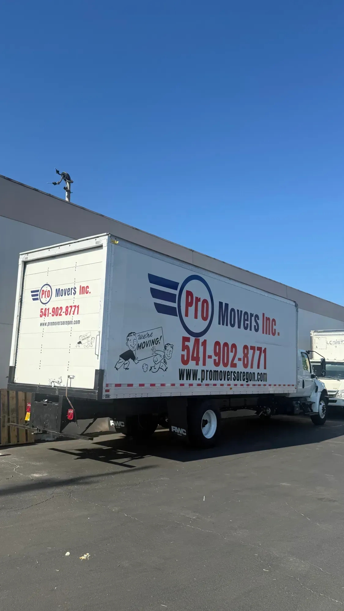 White box truck with Pro Movers Inc. logo parked outside a building on a sunny day.
