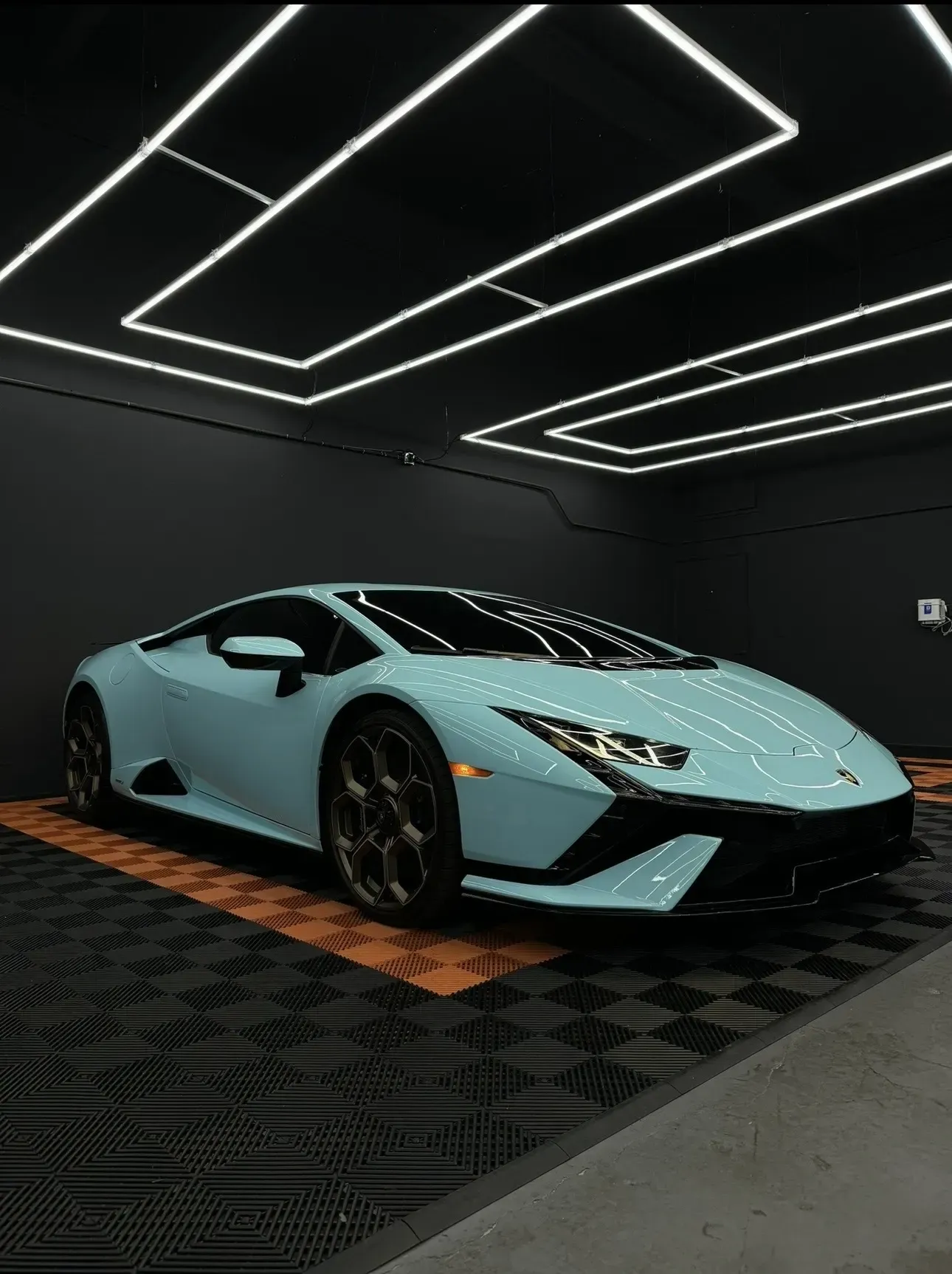 Light blue Lamborghini in a dark garage with neon lights.