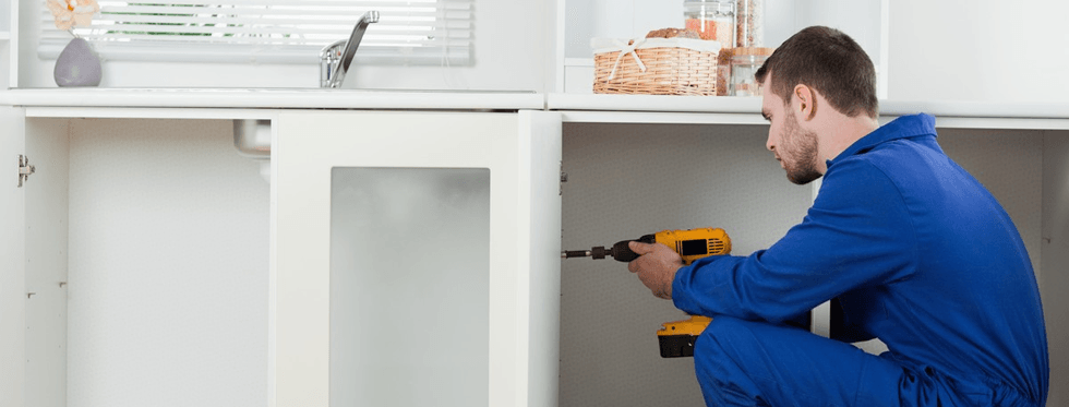 Handyman fixing a door in a kitchen