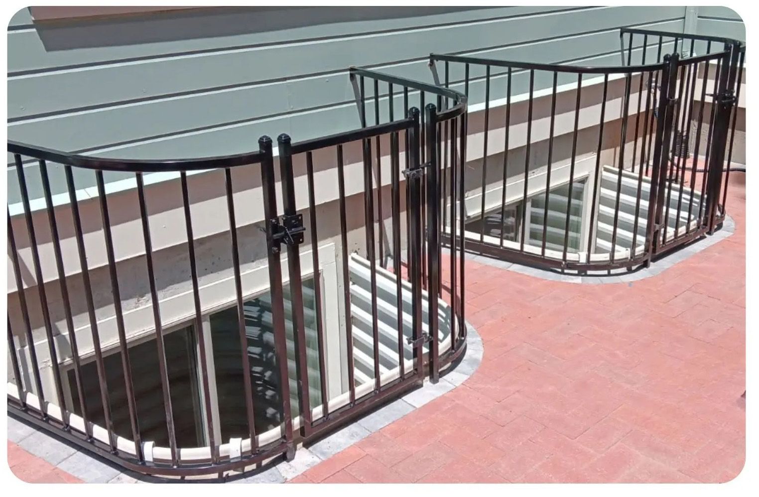 Black metal fences enclose window wells on a red patio, protecting from falls.