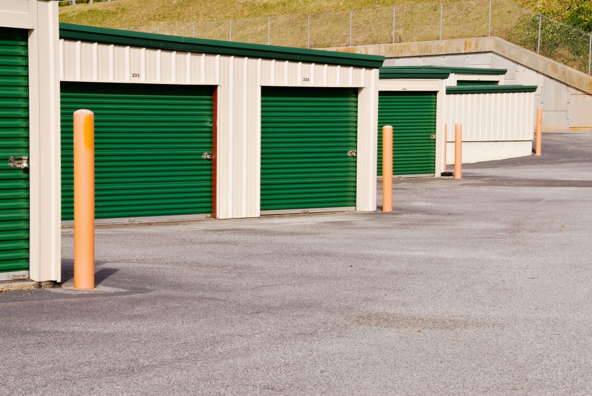 A row of storage units with green doors and orange poles