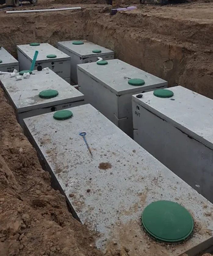 a row of concrete septic tanks are lined up in the dirt