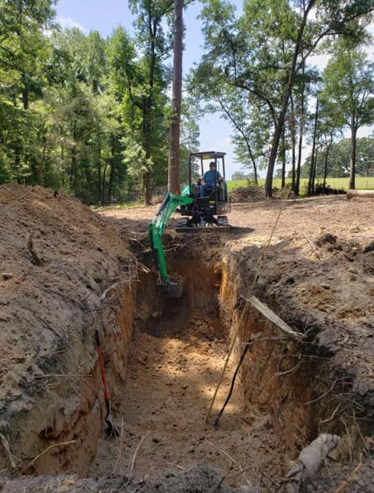 a man is driving a green excavator in a dirt field