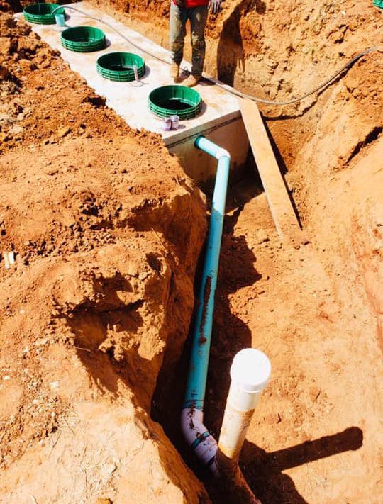 a man is working on a septic system in the dirt